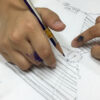 Child's hands sketching a reinvented clock design in a Nanosarte Creative Thinking workshop