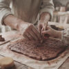 Grandparent and grandchild hands carving heritage symbols in clay at a Nanosarte workshop