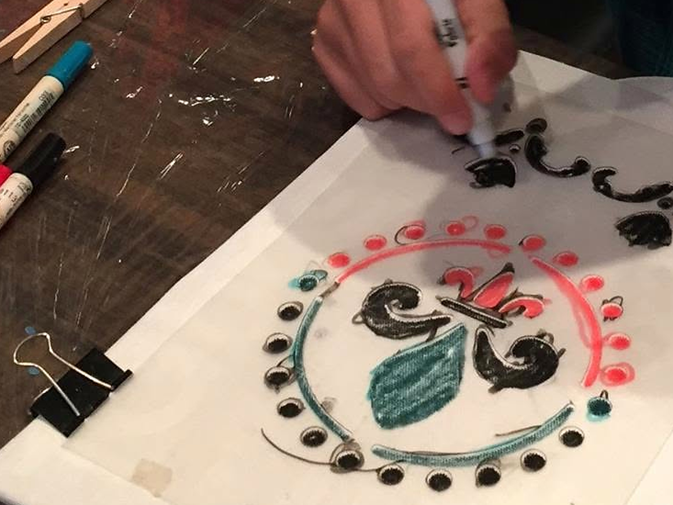 Hands drawing a heritage mandala pattern on fabric at a Nanosarte Wear Your Roots workshop